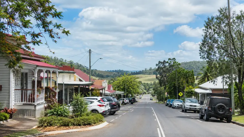 Main street in Imbil, Queensland, with country buildings, parked cars and green Mary Valley hills in the background.
