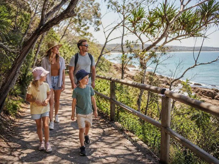 Family walking along a coastal trail in Noosa National Park with children.