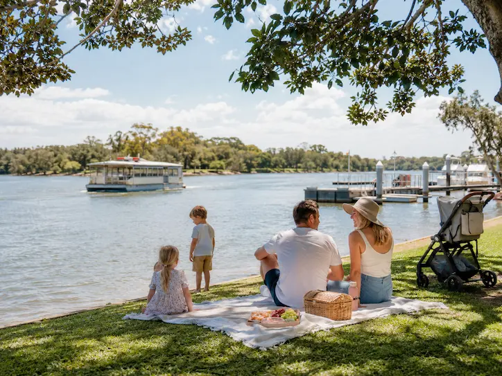 Family picnic by the Noosa River with children playing near the foreshore in Noosaville.