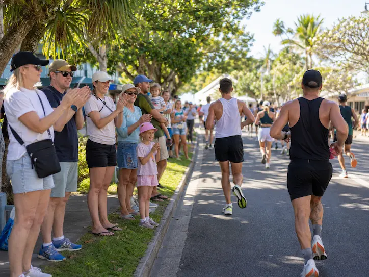 Spectators and families cheering runners from the roadside during the Noosa marathon event.