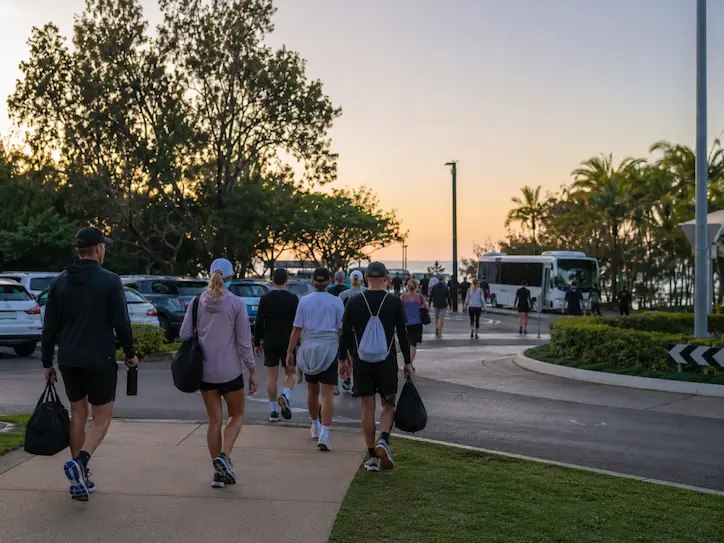 People walking toward the Noosa event area in the early morning near parking and shuttle access during marathon weekend.