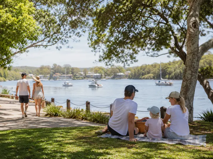 Family relaxing by the Noosa River with picnic views and boats after the marathon weekend.